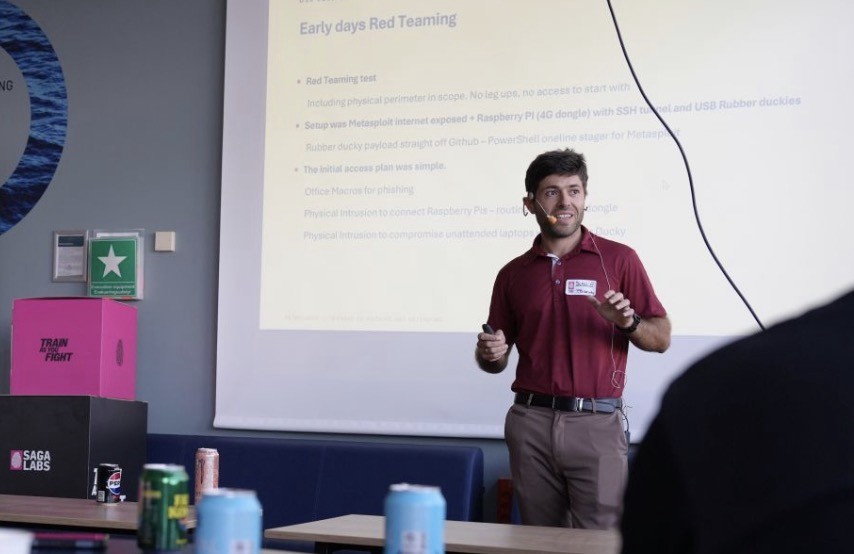 Slavi Parpulev presenting beside a slide headed "Early days Red Teaming", wearing a headset microphone, with a SagaLabs box in the foreground